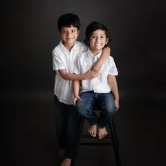 A classic portrait of two brothers. The simple setup with a stool allows their genuine smiles and brotherly affection to be the main story.