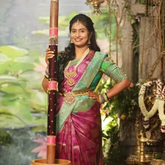 Our beautiful client Pallu celebrating in style. She is wearing a magenta and green silk saree, paired with a custom green blouse that has subtle embroidery work on the sleeves, perfect for a traditional event.