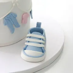 A matching handcrafted blue fondant baby shoe, showcasing the intricate detail of the laces and stitching.