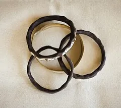 A set of interlocking ceramic bangles with a dark, textured glaze. They make a lovely sound when they move together.