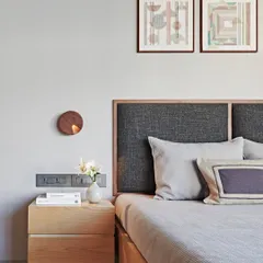 A floating wooden nightstand and a textured fabric headboard create a sense of understated elegance in this bedroom. The soft, neutral finishes and minimalist decor contribute to a timeless and calming interior.