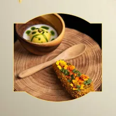 A modern presentation of a classic. This appetizer features a crispy, crumb-coated roll garnished with edible flowers, served alongside a creamy soup shooter in a wooden bowl for a rustic yet refined feel.