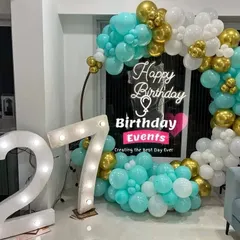 A vibrant and modern take on the ring backdrop, using a striking combination of turquoise, white, and gold chrome balloons. The large marquee numbers for the 27th birthday add a major statement piece.