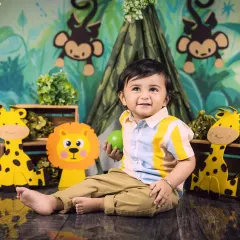 A candid moment of a baby boy playing in his jungle setup, looking off to the side with a happy expression.