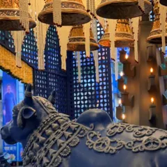 A side view capturing the grandeur of the entrance, with the ornate Nandi, hanging bells, and a custom wall with intricate patterns.