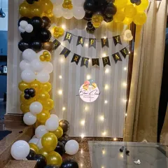 A stylish black, white, and gold balloon frame with fairy lights, perfect for a chic at-home birthday celebration.