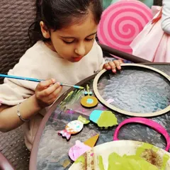 A sweet-themed party in full swing. This little artist is focused on painting her collection of wooden candy and ice cream cutouts, a perfect activity for a fun-filled birthday.