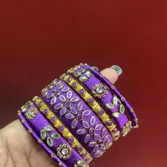 A beautiful bridal bangle set in royal purple, featuring detailed floral threadwork and Kundan stone embellishments. This design is perfect for adding a rich, traditional touch to your look.
