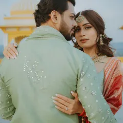 A close, romantic portrait where the bride embraces the groom from behind, showcasing their connection and her Mehendi.