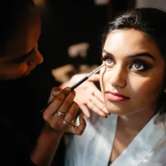 A close-up of the makeup artist applying the final touches. This detailed shot captures the precision and artistry involved in creating the bridal look.
