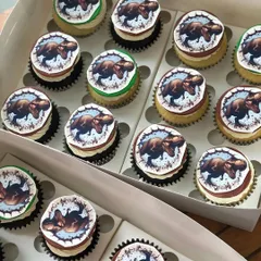 A box of dinosaur-themed cupcakes, perfect to accompany a Jurassic Park or dinosaur birthday cake.