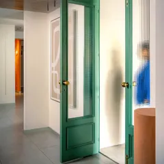 We love using color to make an impact. These tall, reeded glass doors painted in a deep teal create a dramatic entrance to a private consultation room, contrasting beautifully with the neutral interior.