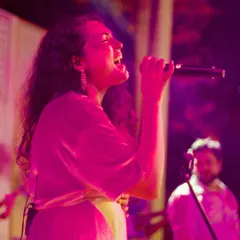 Dhruvi delivering a powerful vocal performance during a wedding reception. The pink lighting and her passionate expression capture the vibrant mood we create.