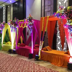 Colorful shamiyana-style seating for a vibrant Mehendi ceremony. We used bright hues of green, yellow, pink, and orange, topped with lush floral arrangements, to create a festive and comfortable space for guests.