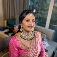 A smiling portrait of the bride during her getting-ready process for the Varapooja. The makeup is almost complete, just waiting for the final touches.