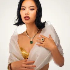 A timeless jewelry portrait. The lighting is focused on bringing out the brilliance of the emerald necklace and the soft glow of the pearls, set against a clean, high-key background for maximum impact.