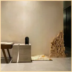 An artistic corner in our office, where we explore the combination of textures. A travertine pedestal, a wooden desk, and a sculptural arrangement of wood blocks create a tactile and visually engaging composition.