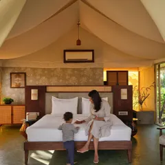 The interior of a glamping tent, where a canvas roof and natural materials create a cozy yet spacious atmosphere. The design combines the rustic appeal of camping with the comforts of a luxury resort room, complete with views of the outdoors.