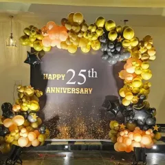 A close-up of the custom "Happy 25th Anniversary" backdrop, framed by a beautiful arch of gold, black, and peach balloons. This setup is perfect for celebrating a silver jubilee in style.