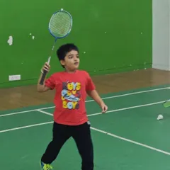 A young player focuses intently as he prepares to hit an overhead shot. My coaching emphasizes correct form and technique from the very beginning.