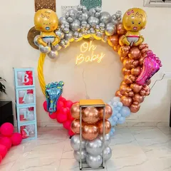 A modern and colorful 'Oh Baby' setup. The circular arch is decorated with balloons in four different colors, with large baby and foot-shaped foil balloons for a playful touch.
