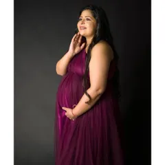 A beautiful solo portrait in a rich magenta gown against a simple black backdrop. This classic studio lighting setup highlights the beautiful curves of the baby bump.