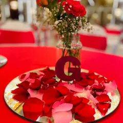 I offer personalized details like this custom centerpiece. It features a mirrored base, scattered rose petals, and a custom initial, which can be adapted to feature a company logo or event monogram for a branded corporate dinner.