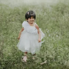A happy, carefree smile captured as she walks through the tall, wispy grass.