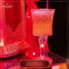 Refresh yourself with Mocktail Magic. This beautifully layered drink, served in a crystal goblet against a festive backdrop, shows how our beverages contribute to the event's ambiance.