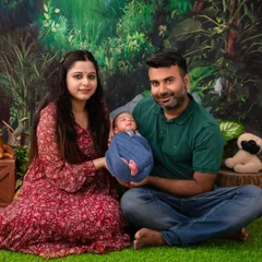 A family sits together against a lush, jungle-themed backdrop, holding their newborn. This image shows how we can incorporate creative themes into family portraits for a unique and memorable result.