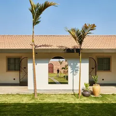 The guest suites at Samavana are arranged around a central lawn, offering a serene retreat from the main festivities. An arched opening in the wall frames a view through to the other side, creating layers of space and visual connection.