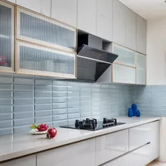 Our kitchens are designed to be the heart of the home, both beautiful and highly functional. Here, we paired sleek, handleless cabinetry with a pop of pastel blue subway tiles and fluted glass shutters, proving that practical spaces can also be full of personality.