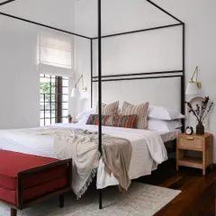 I believe a master bedroom should be a sanctuary. Here, I designed a custom four-poster bed to create a sense of retreat, layering soft textiles and warm wood tones. The arched doorway offers a glimpse into the bespoke walk-in closet, showing how I integrate practical needs into a serene design.