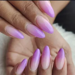 We create seamless color blends with our ombre nail services. This set shows a beautiful fade from a natural base to a vibrant lilac on long, almond-shaped extensions.