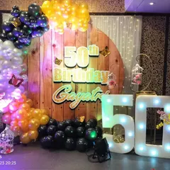 A rustic-themed 50th birthday party decoration. We used a wooden panel backdrop, a colorful balloon arch, and light-up '50' marquee numbers to create this look.