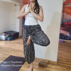 A yoga block is used here to challenge and refine balance in Vrikshasana (Tree Pose). Practicing on an unstable surface like a block strengthens the small muscles in the feet and ankles, improving overall stability and focus.