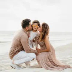 A sweet family photo with both parents kissing their son's cheeks on the beach. A beautiful way to celebrate a milestone birthday.