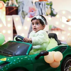 A grand entrance for the birthday girl in a toy car, perfectly matching the Jungle Safari theme. The backdrop features large, illuminated letters spelling her name and a variety of cute animal props.