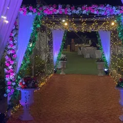 A beautiful floral entrance arch for an evening reception. The combination of pink and white flowers, greenery, and soft lighting creates a romantic and welcoming pathway for guests.