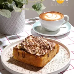 A perfect pairing of coffee and dessert. This shot uses soft, natural light to highlight the texture of the French toast and the latte art, making it an ideal image for a cafe's social media or menu.