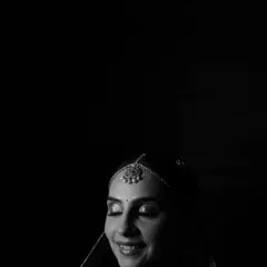 A minimalist black and white portrait, where the focus is entirely on the bride's serene smile and the beautiful play of light on her face.