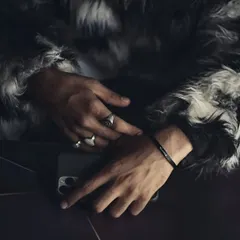 A moody, stylish shot of a man's hands, featuring a black engraved cuff bracelet paired with bold rings. This shows how to incorporate the bracelet into a more fashion-forward, layered look.