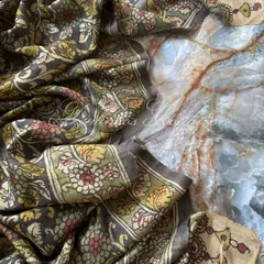 The Kalamkari silk dupatta is artfully draped to showcase its fluidity and the complexity of its hand-painted floral design. The off-white and green border adds a classic touch.