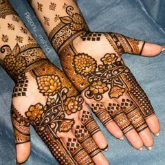 A gorgeous floral design that extends up the arm. The use of negative space with scattered motifs on the forearm contrasts beautifully with the denser patterns on the palm.