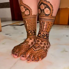 Bridal feet mehndi is essential for the complete look. This design features bold rose motifs on the legs, connected to intricate patterns covering the entire foot, ensuring every detail is perfect.