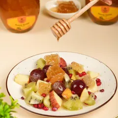 Here we show the product in a use-case scenario, drizzling honey over a fresh fruit salad. This helps customers visualize how they can enjoy the product at home.