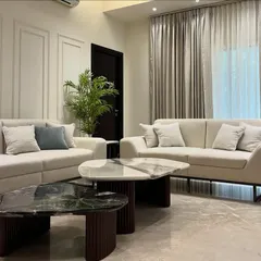 This view highlights the seating arrangement with two sofas and custom stone coffee tables. The design focuses on creating an open, conversational atmosphere perfect for family gatherings.