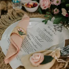 Every detail on the table is crafted to create a feeling of timeless romance. From the custom-printed menu to the delicate floral napkin rings, this setup invites guests to a truly special dining experience.