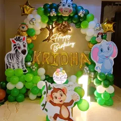 A safari-themed birthday decoration featuring large animal cutouts. We created this setup with a green and white balloon arch, a neon sign, and character props of a monkey, elephant, and zebra.