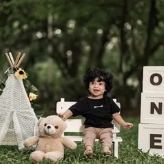 A happy one-year-old enjoying the fresh air. Our outdoor sessions are perfect for capturing natural smiles and joyful moments.